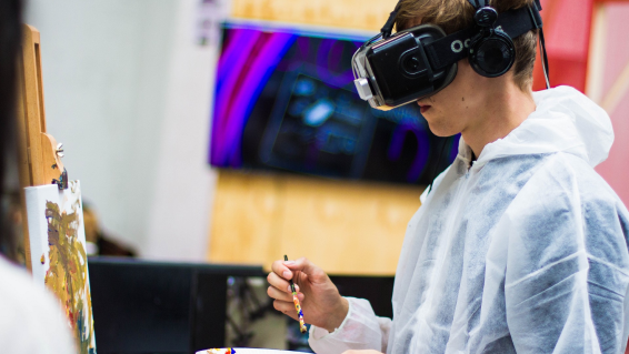 Individual experiencing virtual reality with a VR headset and handheld controllers.